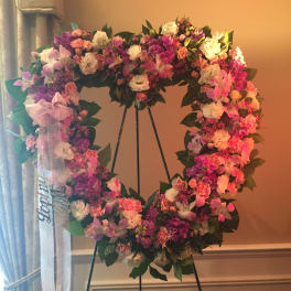 Heart-shaped floral wreath on an easel with a ribbon bow