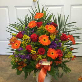 Large mixed bouquet with orange gerbera daisies and red roses in a white container