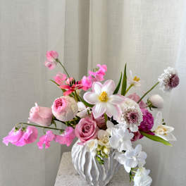 Pink and white floral arrangement in a white textured vase