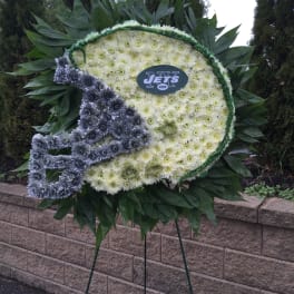 Football-shaped floral tribute on an easel with white and gray flowers