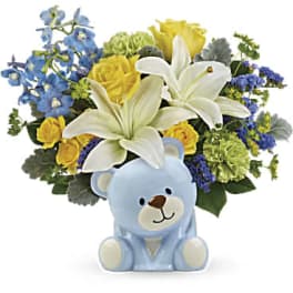 Blue teddy bear with a mixed bouquet of white lilies and yellow roses