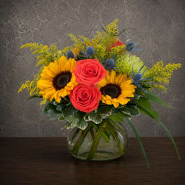 Bouquet of sunflowers and red roses in a glass vase