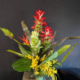Tropical arrangement with red and green blooms in a teal vase
