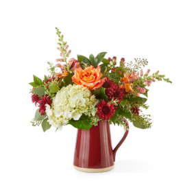Mixed bouquet in a red ceramic pitcher vase with orange and white blooms