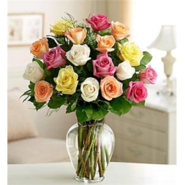 Mixed roses in pink, peach, yellow, and white in a clear glass vase.