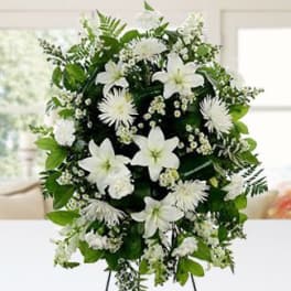 Tall standing spray of white lilies, mums, and carnations on a metal easel