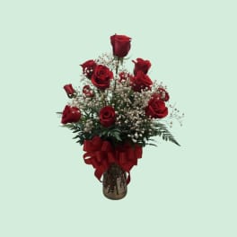 Red roses in a glass vase with baby's breath and a red ribbon