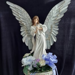 Angel figurine with wings above pastel flowers in a decorative bowl