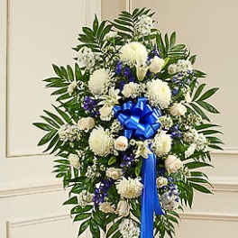 Standing floral wreath of white and blue flowers with a blue ribbon