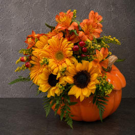 Orange and yellow floral arrangement in a pumpkin container