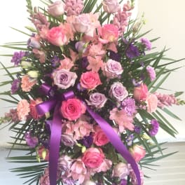 Pink and lavender floral standing spray with a purple ribbon