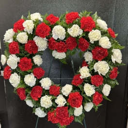 Heart-shaped wreath of red and white carnations on a stand