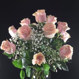 Pink roses arranged in a clear glass vase with white baby's breath
