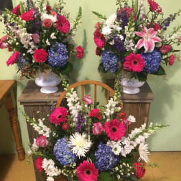Three colorful floral arrangements with gerbera daisies and hydrangeas in white vases