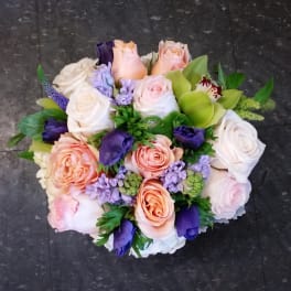 Bouquet of pastel roses, purple blooms, and green orchids