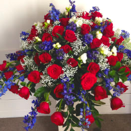 Large bouquet of red roses with blue flowers and white filler in a vase