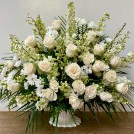 White roses and white daisies in a white pedestal vase