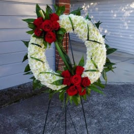 Heart-shaped floral wreath with red roses and white chrysanthemums on a stand