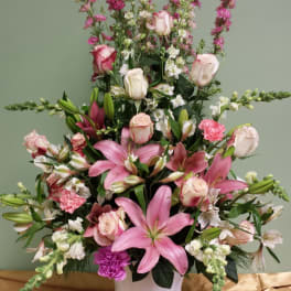 Pink lilies and roses arranged in a white vase