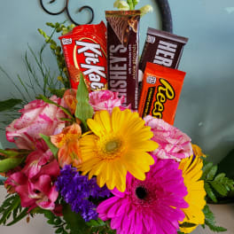 Bouquet of bright flowers with candy bars arranged in the center