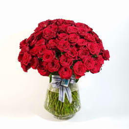 Large bouquet of red roses in a clear glass vase with a striped ribbon