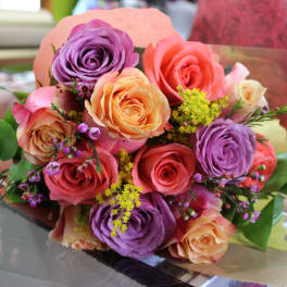 Bouquet of pink, peach, and purple roses with small yellow filler flowers