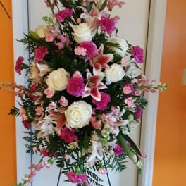Standing floral spray with pink and white flowers on a black easel