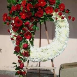 Heart-shaped floral wreath with red and white flowers on an easel
