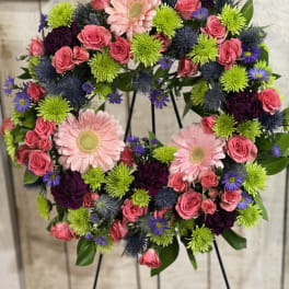 Heart-shaped floral wreath with pink roses and gerbera daisies on a stand