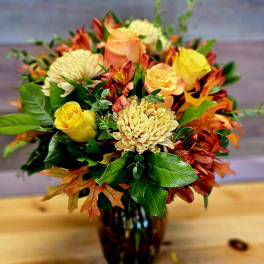 Bouquet of yellow and peach roses with orange flowers in a dark glass vase