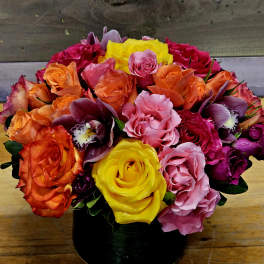 Colorful bouquet of roses and orchids in a black vase