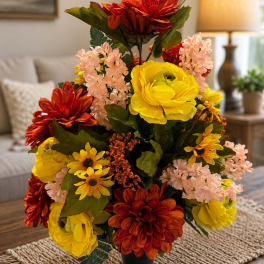 Artificial bouquet of red, yellow, and pink flowers in a black vase