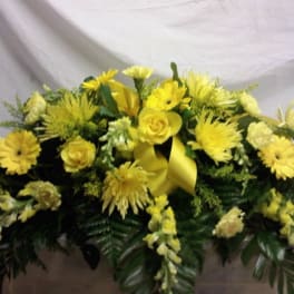 Yellow floral casket spray with roses and daisy-like blooms