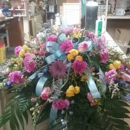 Large colorful funeral spray with pink, yellow, and blue flowers