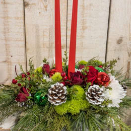 Holiday centerpiece with red candles, roses, and pinecones