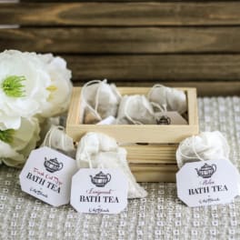 Bath tea sachets in a wooden box beside white flowers