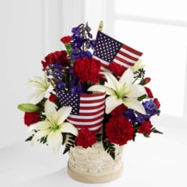 Basket arrangement of red carnations, white lilies, and American flags