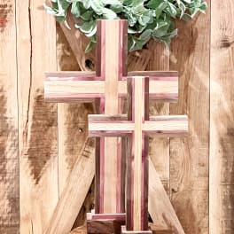 Wooden cross display with a green leafy wreath on a rustic wood backdrop