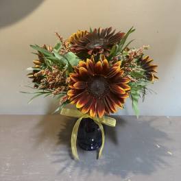 Sunflower bouquet in a dark vase with a yellow ribbon
