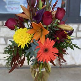 Mixed bouquet in a glass vase with roses, lilies, gerbera daisies, and chrysanthemums