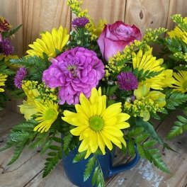 Bright mixed bouquet in a blue mug with yellow daisies and pink roses
