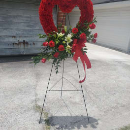 Red heart-shaped floral standing arrangement on an easel with a ribbon