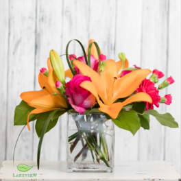 Orange lilies and pink roses in a clear glass vase