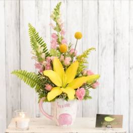 Yellow lily and pink flowers arranged in a mug with a baby girl design