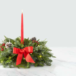 Holiday centerpiece with a red taper candle and evergreen wreath