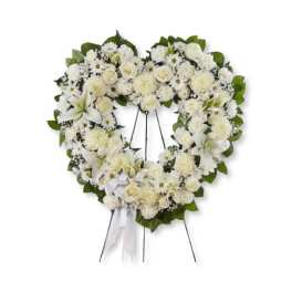 Heart-shaped white floral wreath on a stand with ribbon