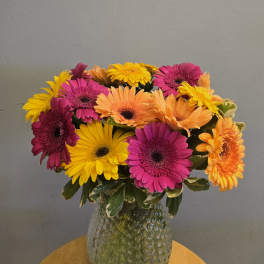 Bright gerbera daisy bouquet in a textured glass vase
