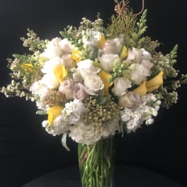 Bouquet of white and pale pink roses with yellow calla lilies in a glass vase