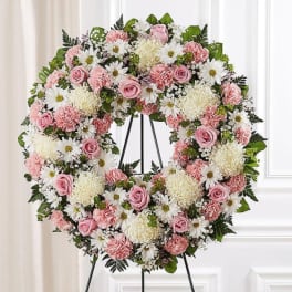 Pink and white floral wreath on a black stand