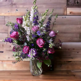 Pink and purple roses with white and purple snapdragons in a glass vase